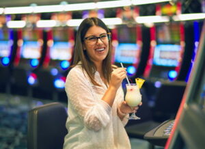 woman playing slots with alcoholic drink