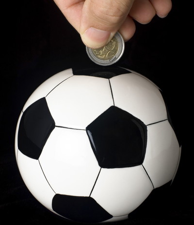 putting money in a football shaped piggy bank