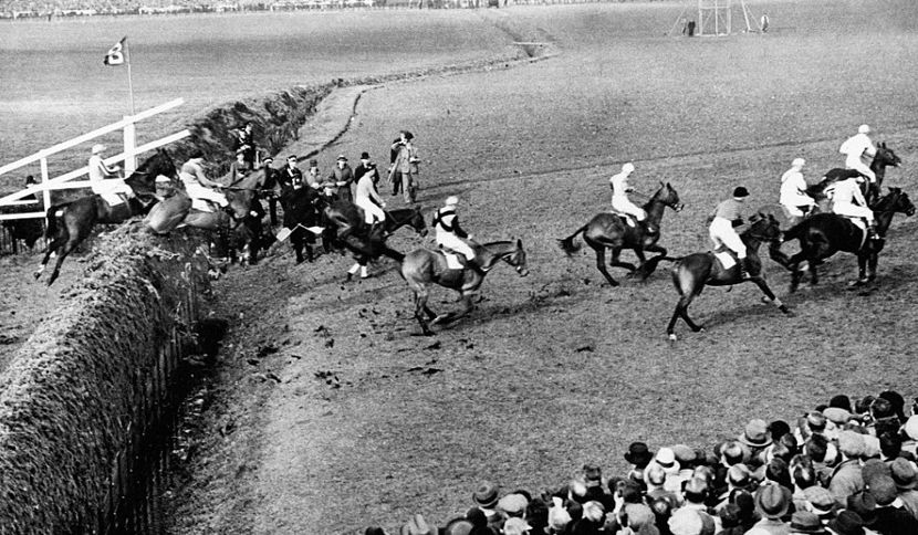 horses jumping a fence at the aintree grand national
